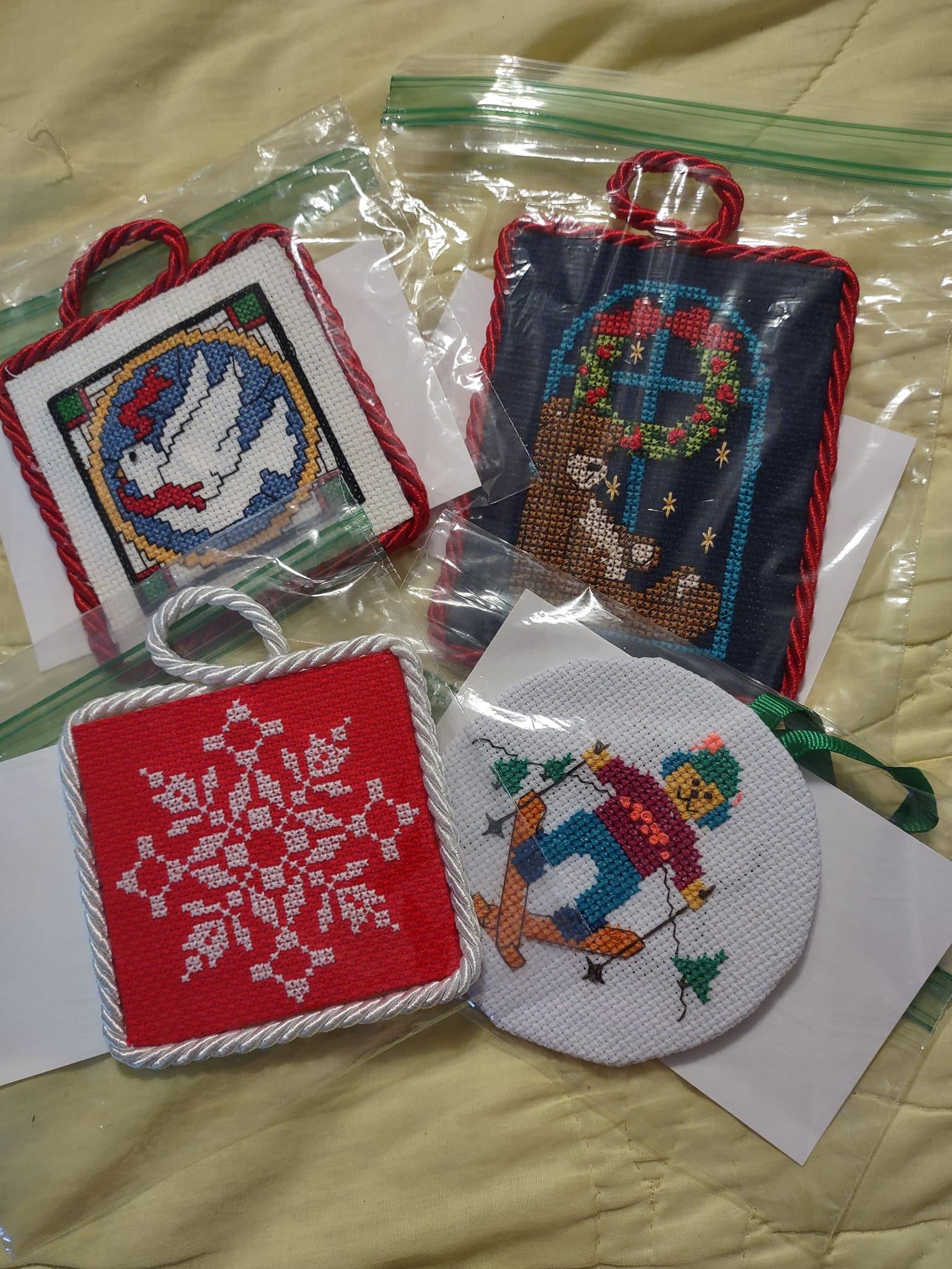 Cross-stitched Christmas designs. Some have cotton rope or twine around the borders.