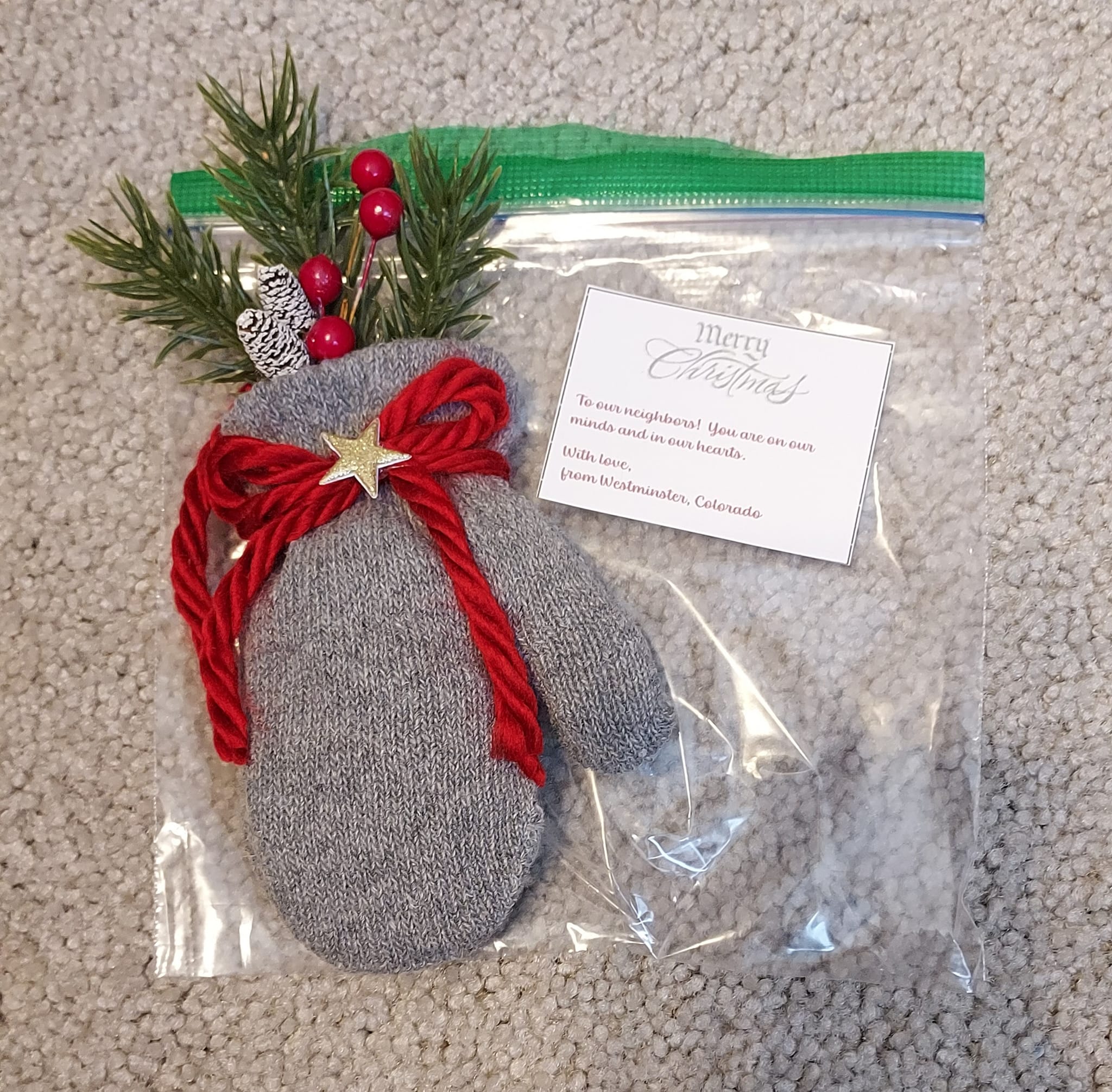 A baby's glove turned into an ornament and decorated with plastic holly and a bow.