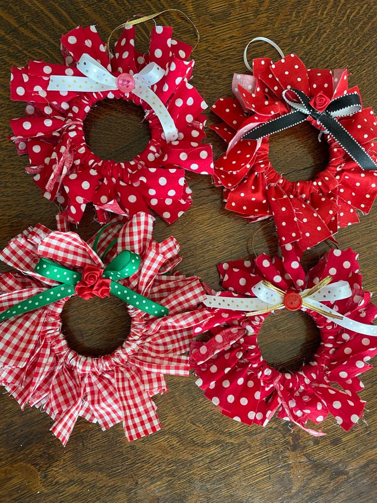 An ornament made with strips of red fabric tied around a ring to form a wreath.