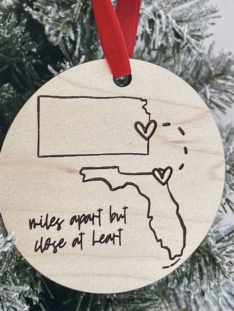 A wooden disc ornament that says "Miles apart but close at heart".