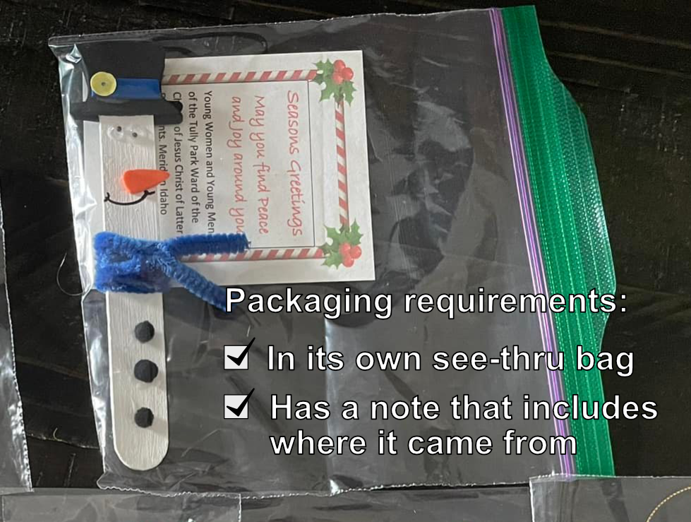 A popsicle stick snowman ornament with a tag and plastic bag.