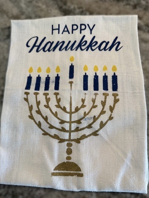 A challah cover with an image of a menorah and the words "Happy Hanukkah".